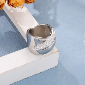 Macro shot of silver wide band ring with pave-set zircons on a textured blue background