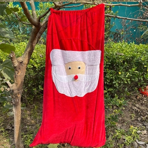 Detail of red velvet Christmas gift bag with 3D Santa applique hanging on a branch