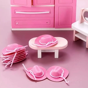 Miniature pink flocked cowboy hats with white ropes arranged in a dollhouse scene