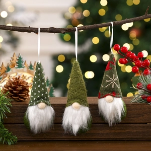 Three Christmas knitted gnome hanging ornaments on a branch with soft festive lights