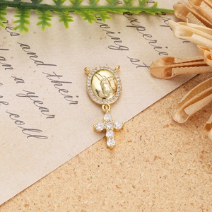 Detailed view of a gold Virgin Mary pendant with a zircon cross on vintage letter paper