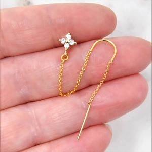 Macro shot of gold S925 silver chain earring with clover zircon detail on a finger