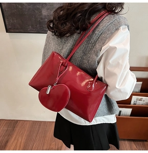 Detail of glossy red faux leather shoulder bag featuring a matching heart-shaped coin purse