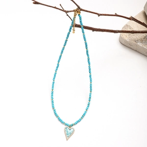 Detail view of heart pendant with turquoise inlay on bohemian beaded necklace
