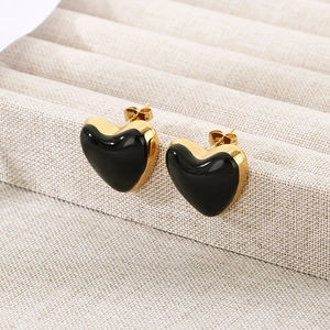 Detail of heart-shaped black enamel earrings with gold plating on a jewelry tray