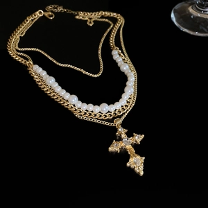 Close-up of vintage gold multi-layer necklace with cross pendant and pearls