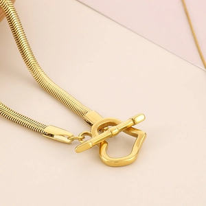 Detail of golden heart-shaped OT toggle clasp on a sleek snake chain necklace