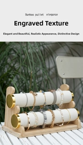 Close-up of double-tier bamboo jewelry display stand with white velvet rolls and gold caps