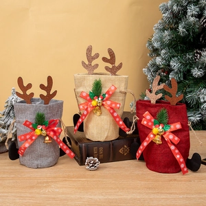 Three Reindeer Christmas gift bags with snowflake ribbons and bells on wooden table