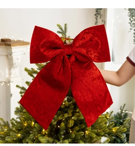 Detail of a large red velvet Christmas bow as a decorative topper for a festive holiday tree