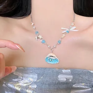 Detail shot of ocean theme beaded necklace with blue shell pendant on a model's neck