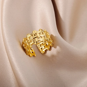 Macro view of gold-plated braided ring with woven texture on champagne silk fabric
