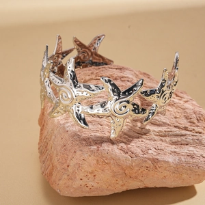 Macro detail of silver starfish open cuff bracelet on natural reddish rock texture