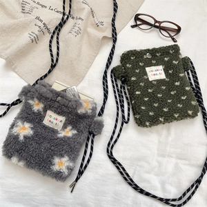 Fleece crossbody bags with daisy and heart patterns next to glasses and a French menu
