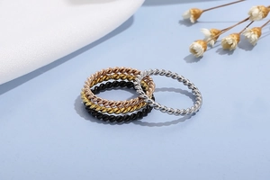 Close-up of four thin twisted rope rings in rose gold, gold, silver and black colors