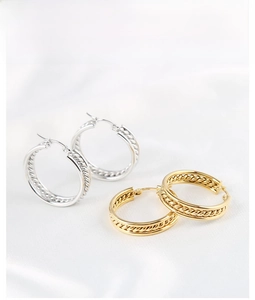 Detailed view of large braided rope hoop earrings in gold and silver finishes
