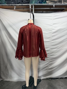 Detail of red long sleeve blouse showing metallic vertical stripes and tiered ruffle cuffs