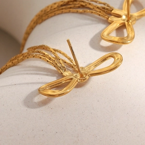 Macro detail of 18K gold plated bow earrings featuring delicate fine chain tassels