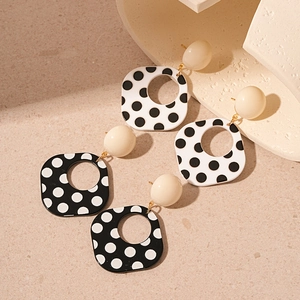 Vintage acrylic black and white polka dot square earrings on a stone textured background