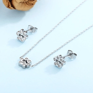 Detailed view of silver stainless steel paw print necklace and stud earrings set with crystals