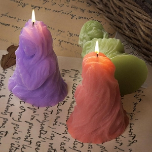 Gros plan de trois bougies portraits drapées en cire violette, verte et orange