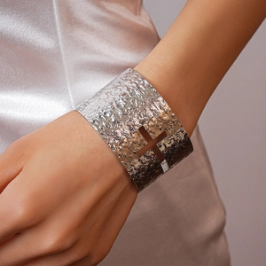 Close-up of silver wide cuff bracelet with hammered texture and cross cutout design