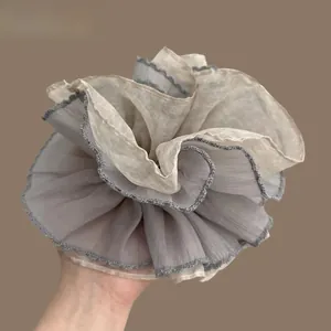 Detail of a large layered chiffon hair scrunchie with grey and beige pleated fabric