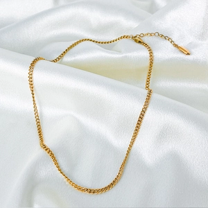 Macro shot of 14k gold plated cuban link chain with extension and logo tag on silk
