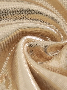 Macro shot of metallic champagne gold swimsuit fabric with fine shimmering texture