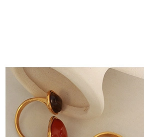 Detail of vintage gold rings with emerald-cut amber and orange gemstones on textured base