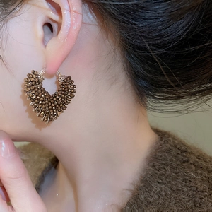 Close-up of vintage heart-shaped crystal beaded hoop earrings on a model