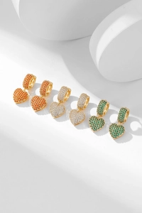 Close-up of heart-shaped drop earrings with micro-pave orange, white, and green zircons