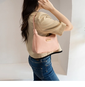 Pink minimalist faux leather underarm shoulder bag worn by model in a studio setting