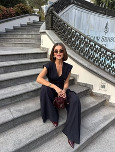 Detail of dark pinstripe vest and wide-leg trousers set with burgundy leather handbag