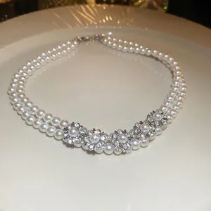Double-layer pearl necklace with sparkling rhinestone flower charms on white ceramic plate