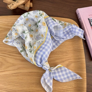 Detailed view of floral daisy and blue checkered linen bandana on a wooden tray
