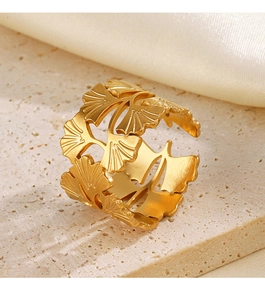 Gros plan d'une bague feuille de ginkgo dorée avec textures sur surface en pierre