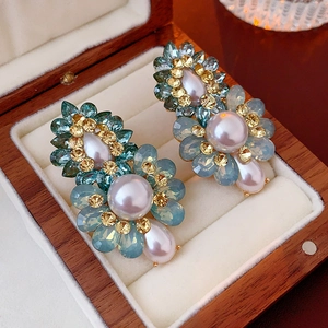 Détail des boucles d'oreilles fleurs en perles et cristaux bleus dans un écrin en bois
