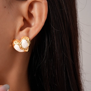 Detailed close-up of golden heart-shaped stud earring with creamy white enamel drip design