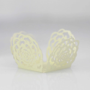 Detailed laser-cut cream cupcake wrapper with intricate rose patterns for wedding decor
