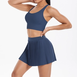 Side view of dark blue athletic yoga set featuring cross-back sports bra and pleated skirt