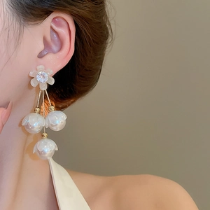 Élégantes boucles d'oreilles fleur avec perles blanches et cristaux portées par un modèle