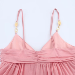Detail of pink camisole dress with golden metal rings and pleated V-neckline texture