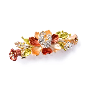 Detailed close-up of floral hair clip with orange enamel and sparkling rhinestones