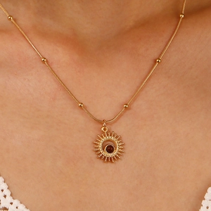 Close-up of golden sun pendant necklace with tiger eye stone on beaded snake chain