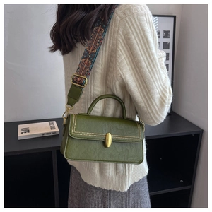 Detail of vintage green square bag with golden hardware and ethnic embroidered strap