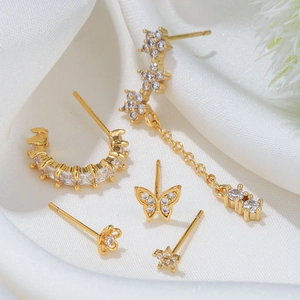 Detail of five-piece gold butterfly and flower stud earring set with zircon accents