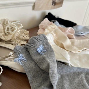 Detail of knitted cotton mid-calf socks with blue ribbon bows on wooden background