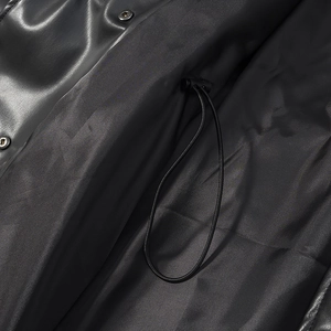 Detail of adjustable drawstring toggle and premium PU leather texture on black trench coat