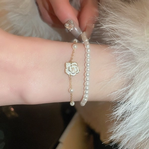 Détail d'un bracelet double couche avec fleur de camélia en émail et perles d'imitation